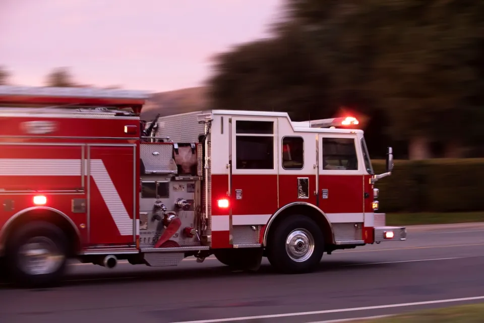 Red fire truck speeding down a street.